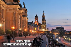 Un edificio histórico con arquitectura clásica, una imponente torre de campanas y un puente al fondo.
