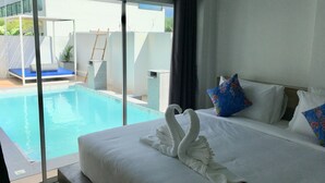 A modern hotel room with a large bed, a swan-shaped towel, a pool, and a view of the outside.