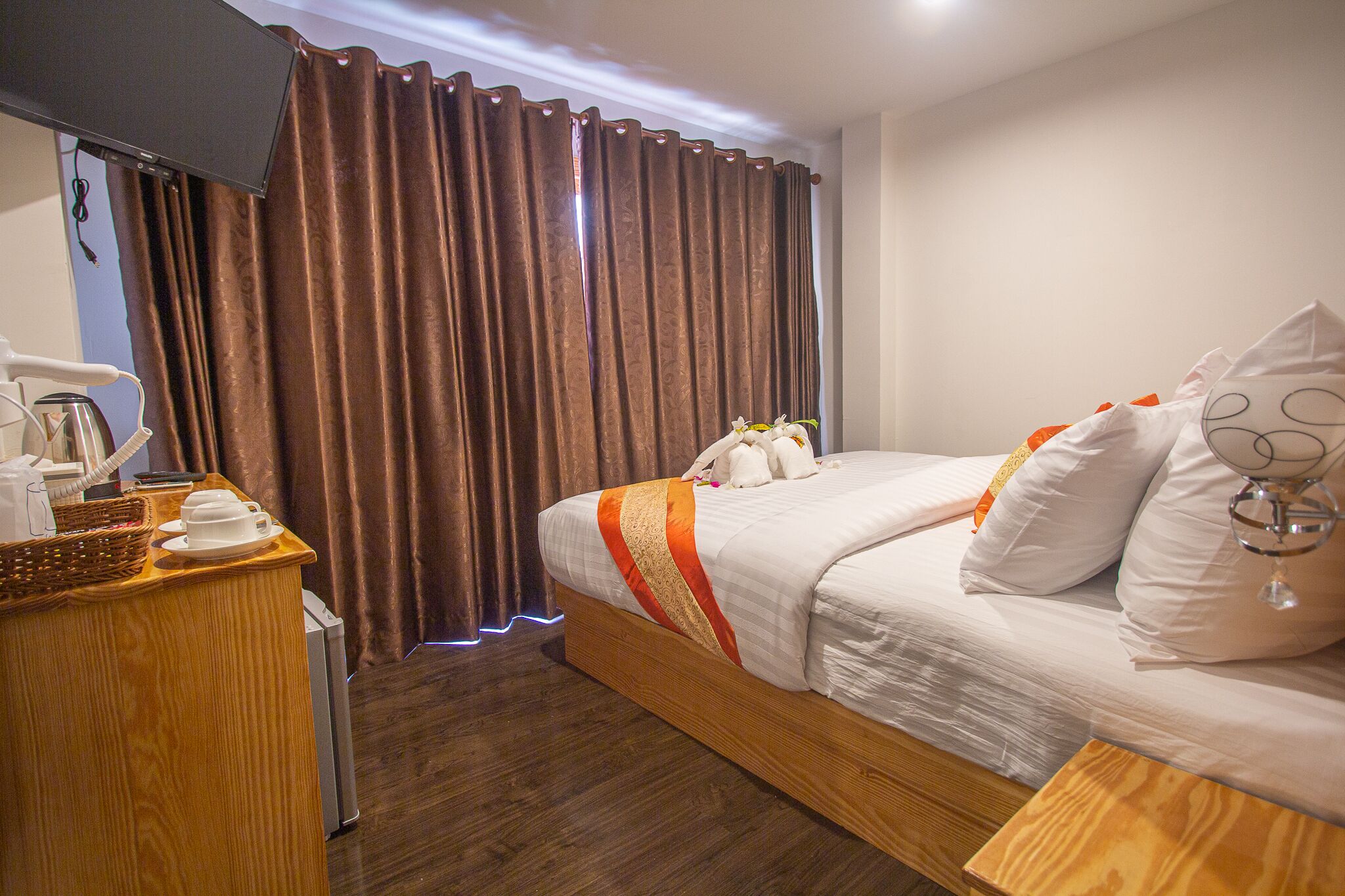 A hotel room with a wooden bed, white bedding, and a bedside table with a lamp.