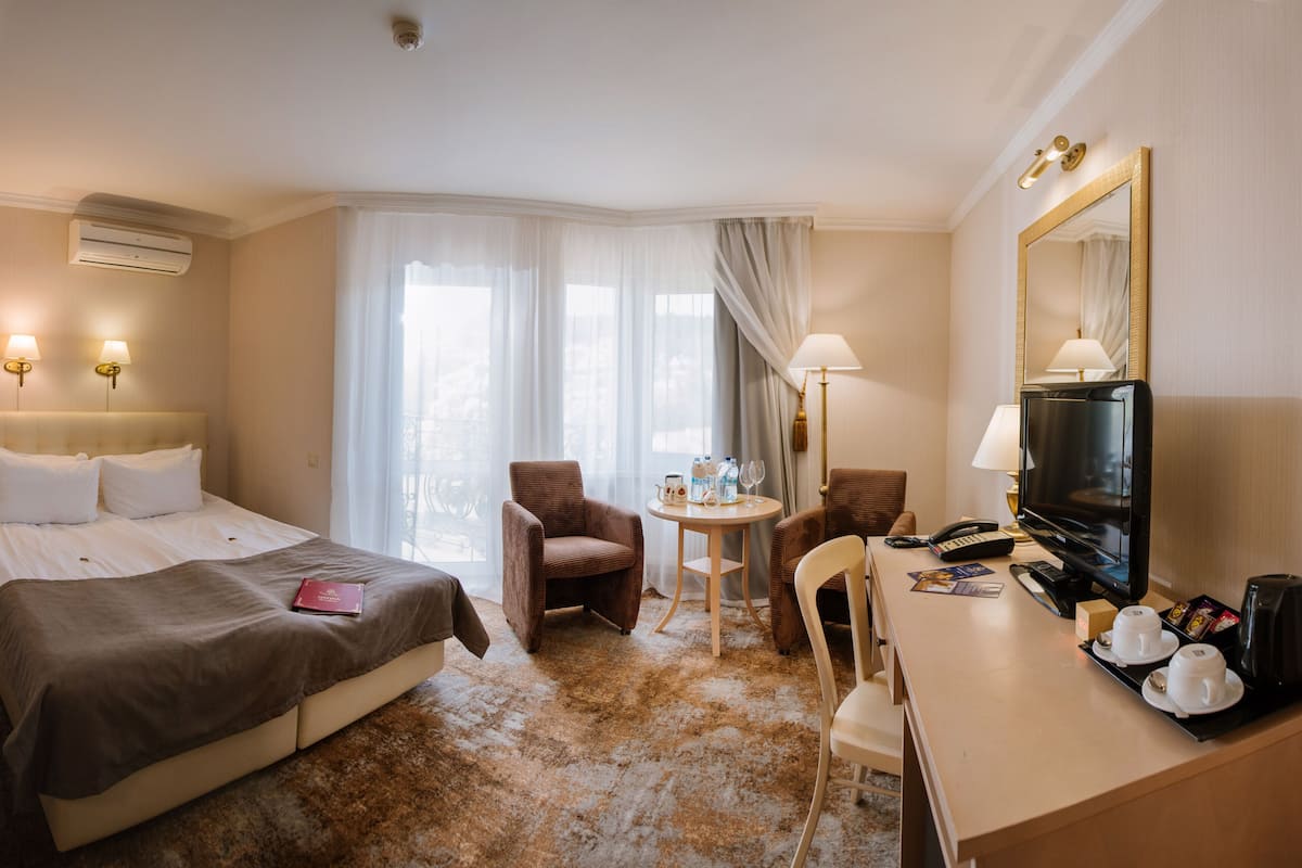 Ein Hotelzimmer mit einem Bett, zwei Stühlen, einem Schreibtisch mit Fernseher und einer Minibar.