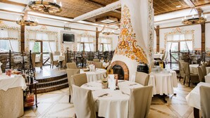 Un restaurante con mesas redondas, sillas, chimenea y un escenario.