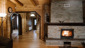 Una sala de estar acogedora con chimenea de piedra, pisos de madera y un reloj visible en la pared.