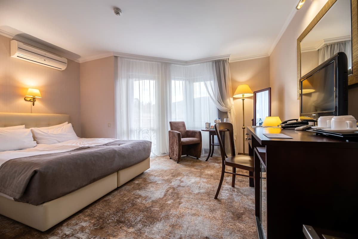 Ein Hotelzimmer mit Bett, Schreibtisch, Stühlen und einem Fernseher.
