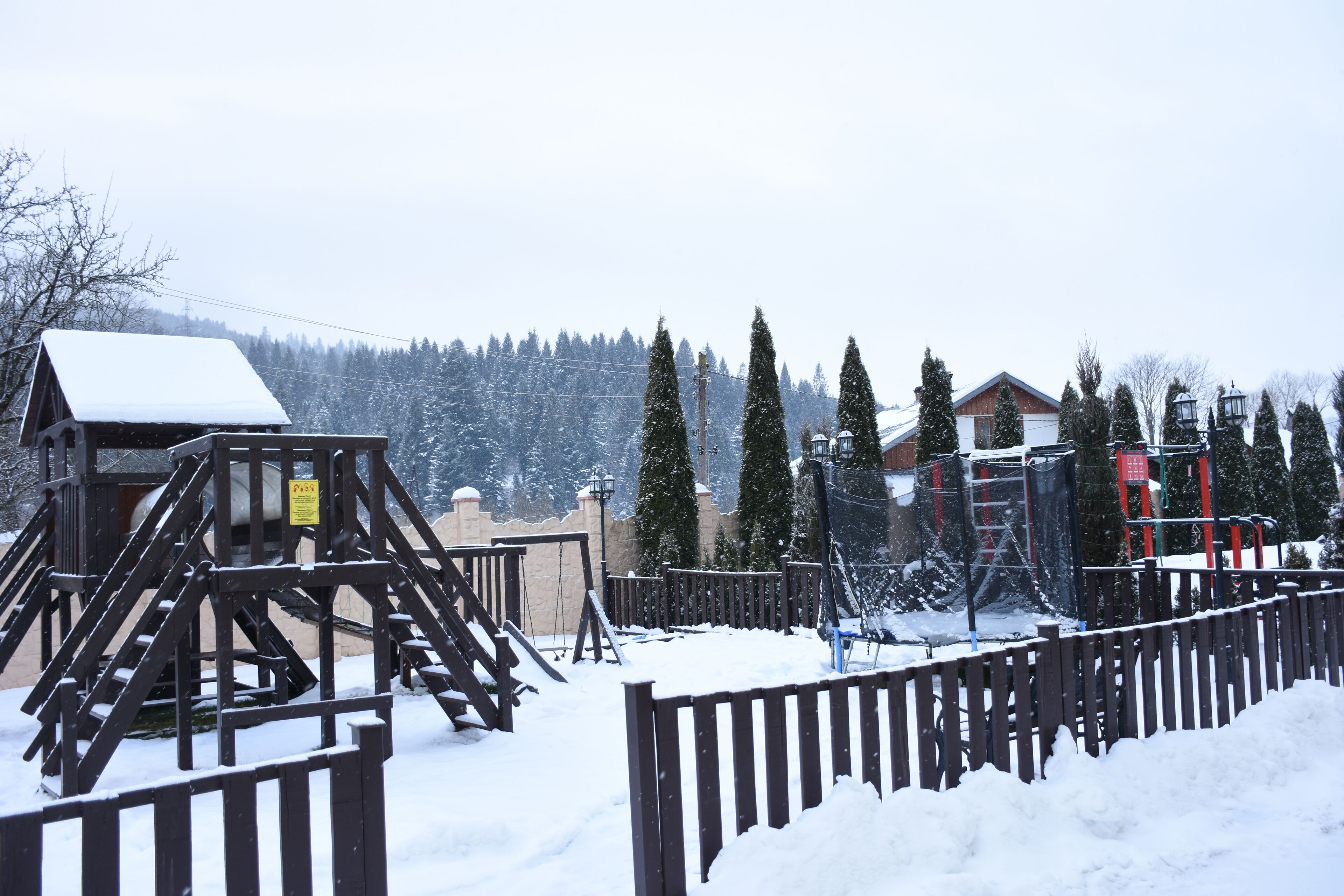 A snow-covered outdoor area with wooden structures and a fenced walkway.