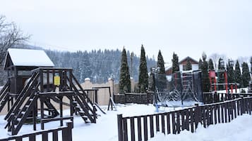 A snow-covered outdoor area with wooden structures and a fenced walkway.
