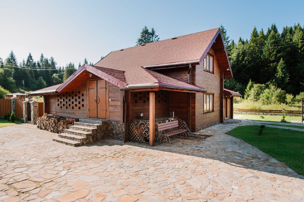 Ein zweistöckiges Holzhaus mit gepflasterter Auffahrt und einer Holzterrasse.