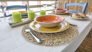 A dining table set with a bowl, plates, cutlery, and candles.