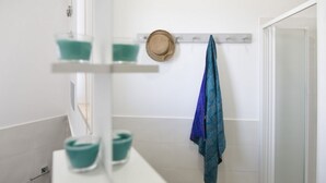 A bathroom with a white sink, a mirror, and a towel rack with a blue towel.