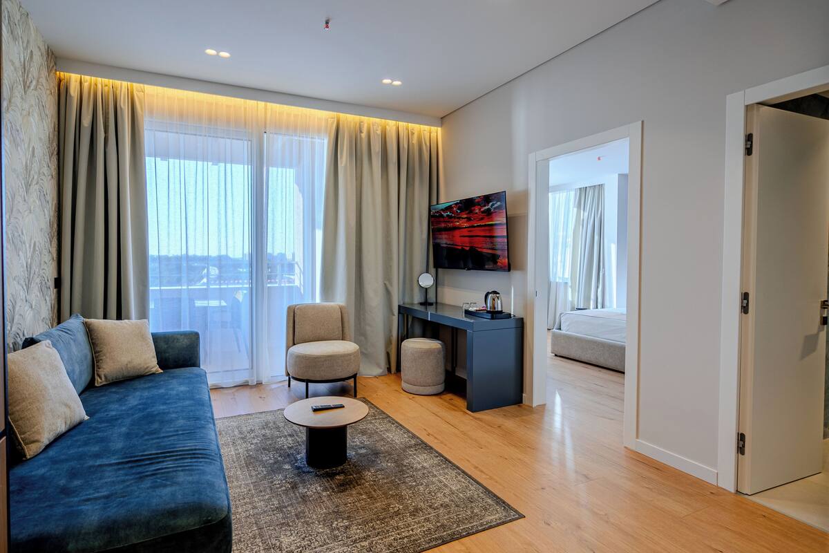 A modern living room with a sofa, a coffee table, a TV, and a desk.