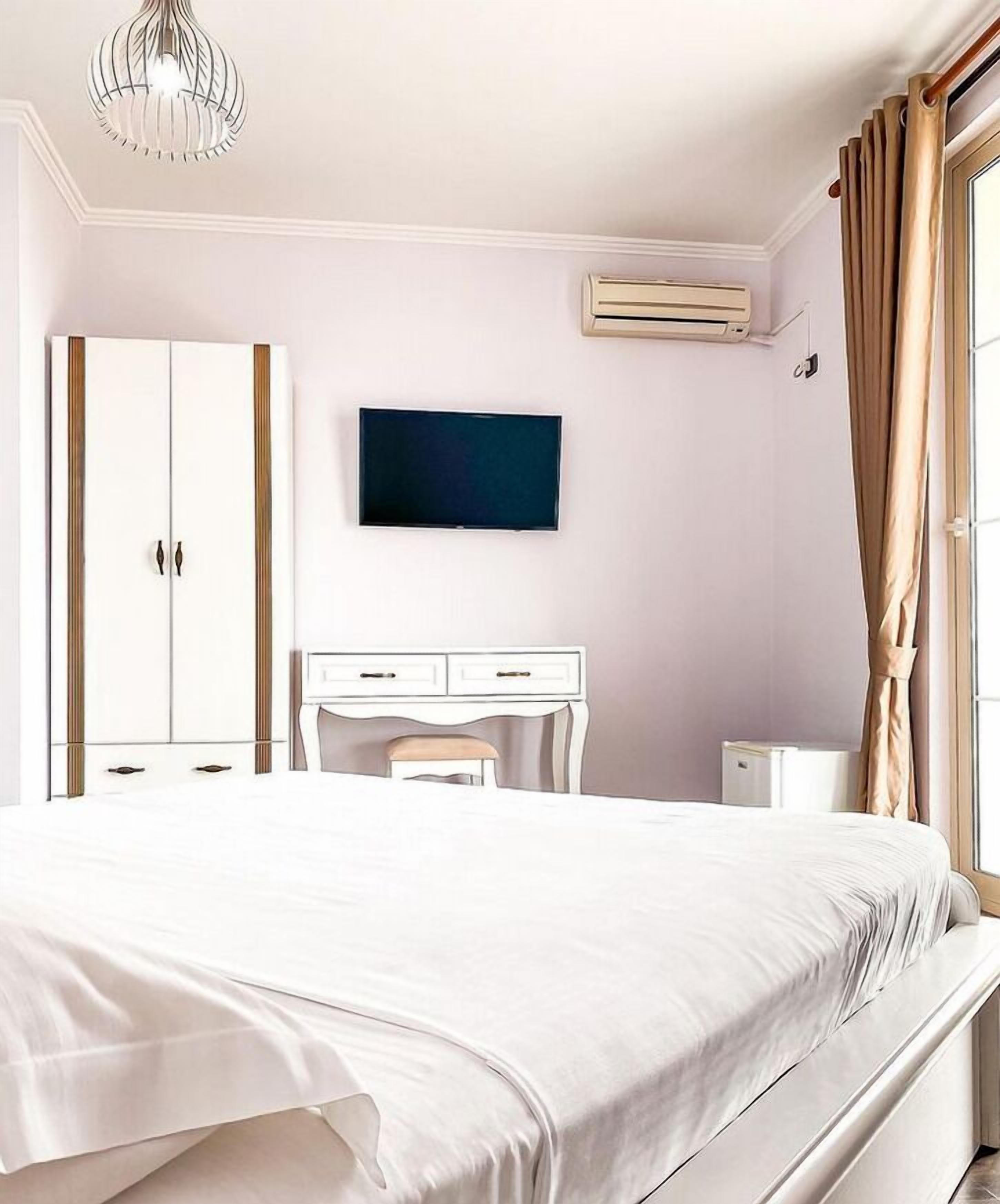 A bedroom with a bed, a TV, a wardrobe, and a desk.