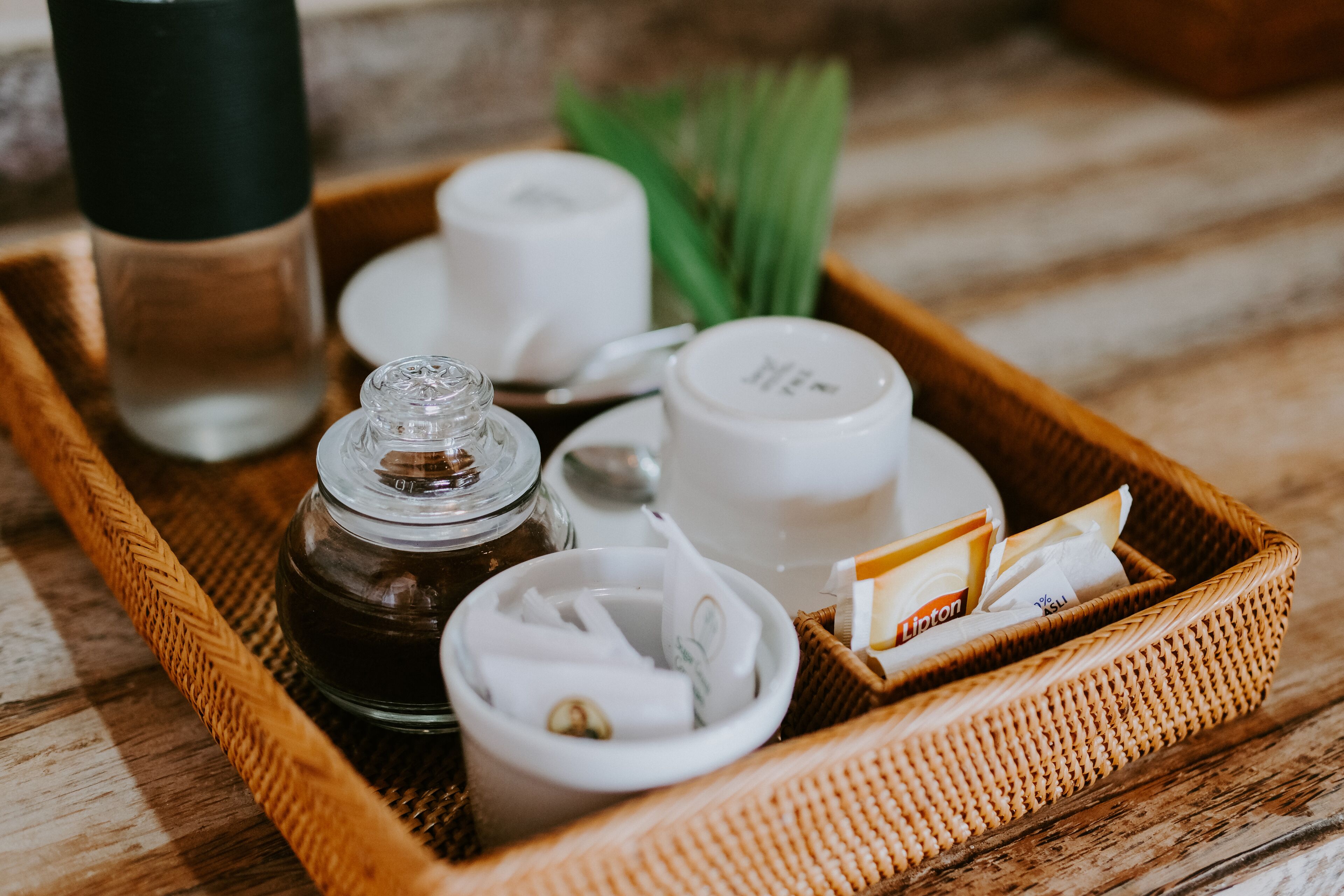 A tray with a glass jar, two white cups, a small bowl, and a Lipton tea packet.