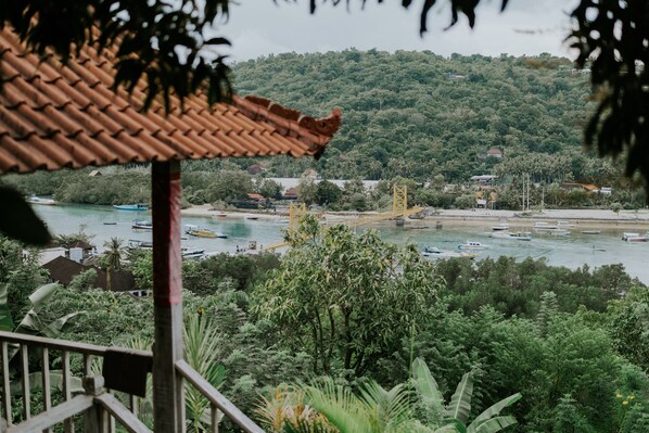 A view of a coastal area with boats on the water, a bridge, and lush greenery.