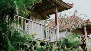 Un edificio de madera con balcón, rodeado de exuberante vegetación tropical.