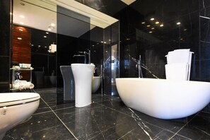 Een moderne badkamer met een vrijstaand bad, een aparte wastafel en een toilet.