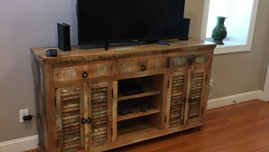 Eine Holzunterhaltungsecke mit Flachbildfernseher, Lautsprecher und Fernbedienung.