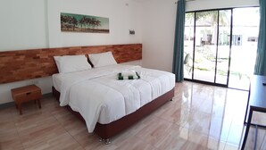 A hotel room with a large bed, a wooden headboard, a small bedside table, and a large window with a view of the outside. - Chinita Boutique Hotel (Dauis)
