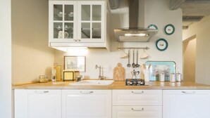 A kitchen with white cabinets, a sink, a stove, and various utensils. - A delightful apartment for 5 people in the heart of San Frediano and close to Piazza S. Spirito (FIrenze)