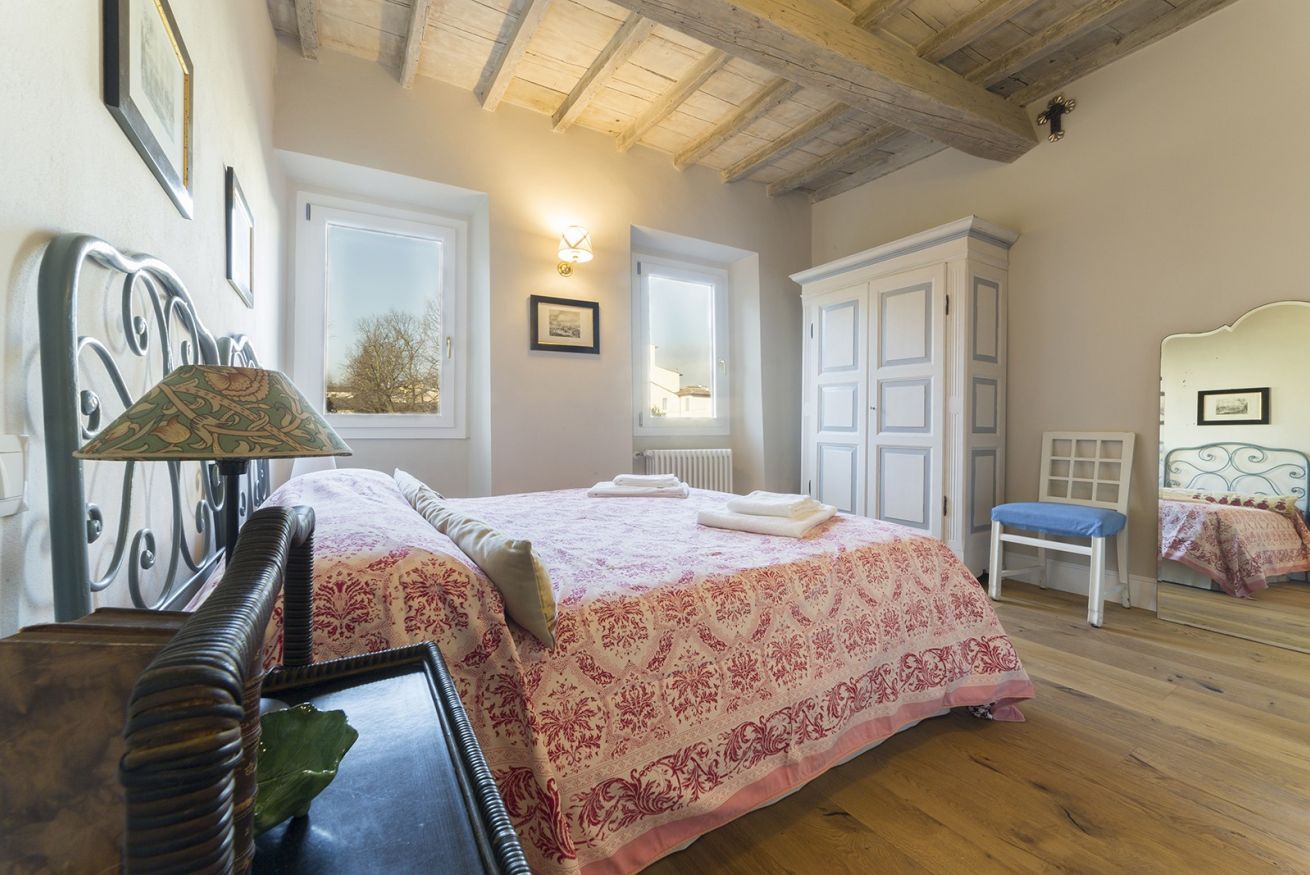 Une chambre à coucher avec un lit, des tables de chevet, une chaise et une fenêtre.