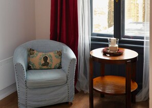 Relax in a cozy corner with a comfortable armchair and a side table, perfect for enjoying the serene view.
