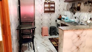 Una cucina compatta con piano di lavoro in marmo, lavello e un piccolo angolo pranzo con tavolo e sedie.