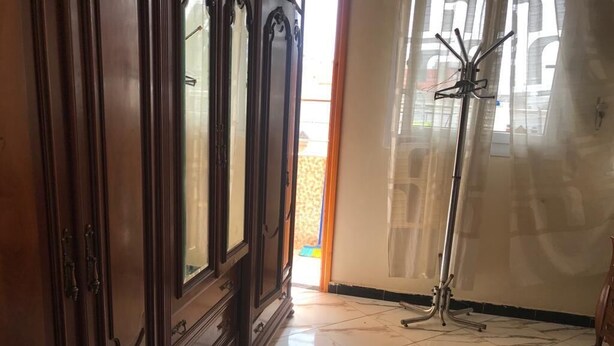 Una stanza con un armadio in legno, un attaccapanni e un pavimento piastrellato.