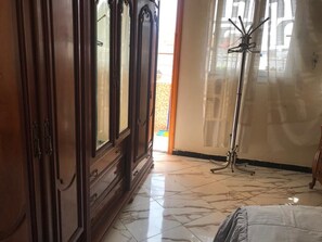 A room with a wooden wardrobe, a coat rack, and a tiled floor. - Appart Qadessia (Marrakech)