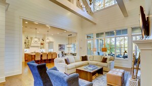 A spacious living room with a large sectional sofa, a coffee table, and a fireplace. There is a dining area with a kitchen in the background. - 85 Mooring Buoy -Dock, Private Pool & Lagoon Views. 176 Yards to the ocean (Hilton Head Island)