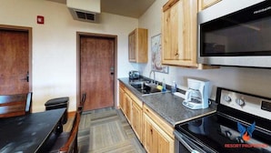 A compact kitchen with wooden cabinets, a built-in microwave, and a coffee maker.