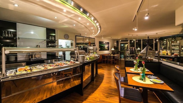 A buffet-style restaurant with a curved counter, multiple seating areas, and a modern interior design. - Hotel am Nikolaiort (Osnabrueck)