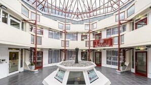 A hotel lobby with a central atrium, multiple floors, and a reception desk. - Hotel am Nikolaiort (Osnabrueck)