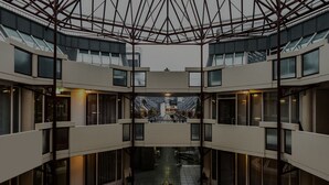 A modern building with a central atrium, multiple floors, and large windows. - Hotel am Nikolaiort (Osnabrueck)