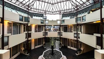 Ein modernes Atrium mit Glasdach, mehreren Etagen und einer zentralen Wasserspüle.
