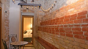 Une pièce chaleureuse avec un mur en briques, une porte en bois, une table ronde et deux chaises.