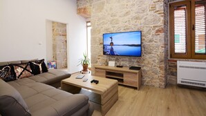 Un salon avec un mur en pierre, un téléviseur à écran plat, une table basse en bois et un canapé.