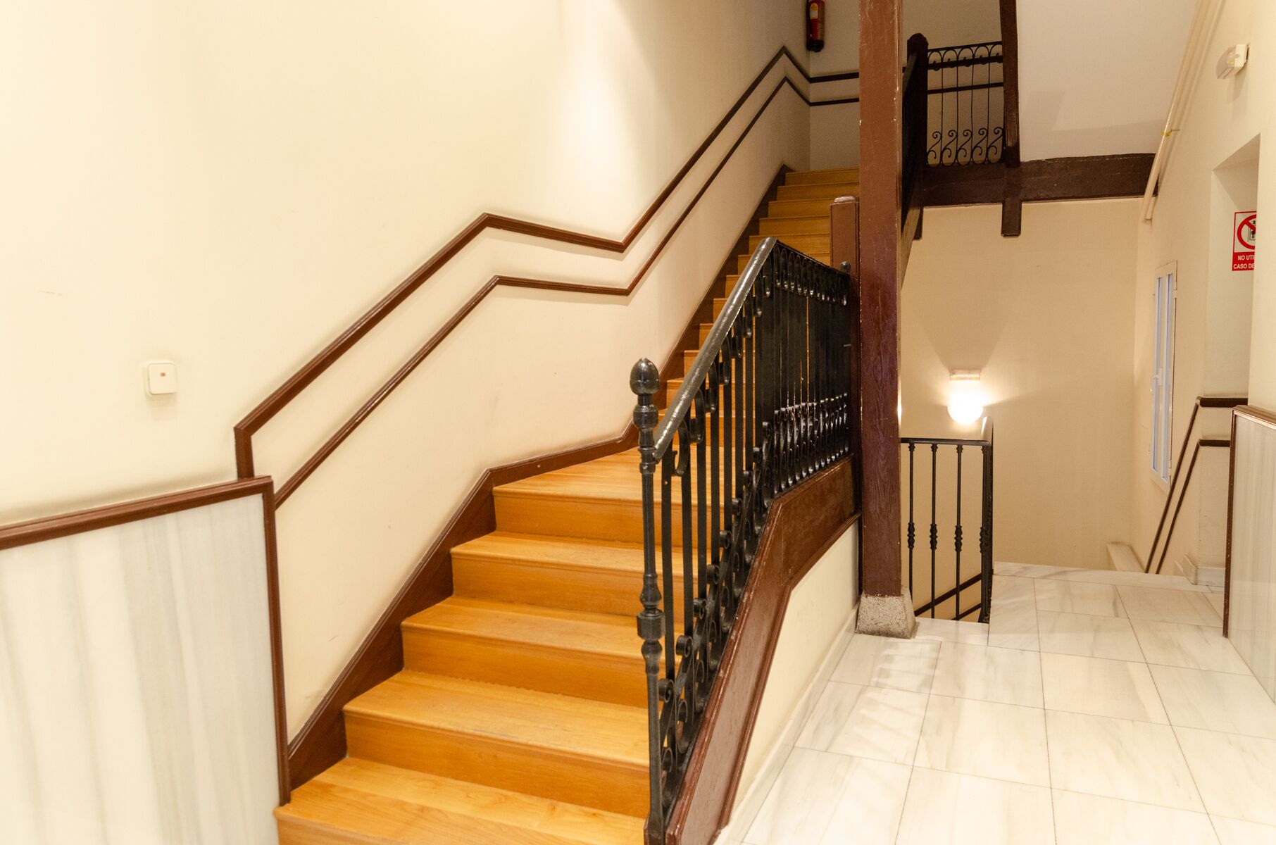 Una escalera de madera con barandillas de metal negro que lleva a un piso superior.