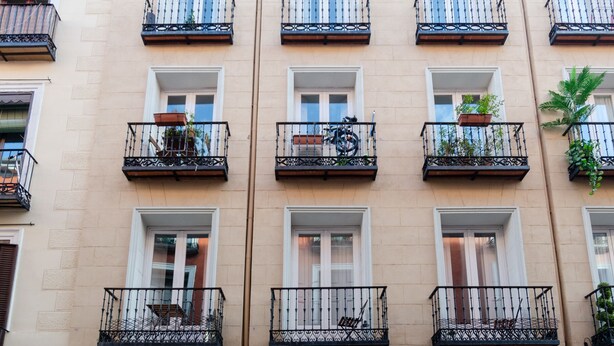 Un edificio de varios pisos con balcones, cada uno decorado con una pequeña maceta.