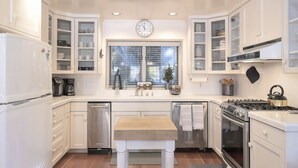 A modern kitchen with white cabinetry, a central island, a stove, and a dishwasher.
