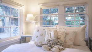 A bedroom with a bed, pillows, a lamp, and a window.