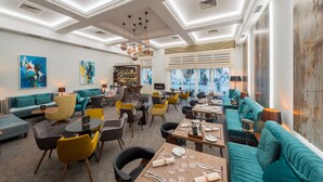 A modern dining area with teal sofas, yellow and gray chairs, and a bar area with a wine rack. - Hotel Waldinger (Osijek)