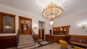 A grand lobby with a marble staircase, a reception desk, and a chandelier. - Hotel Waldinger (Osijek)