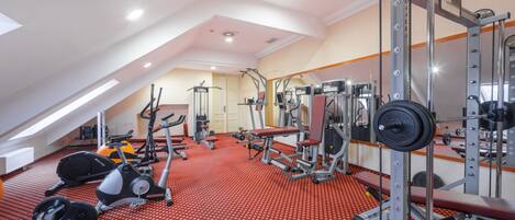 A gym with various exercise equipment, including treadmills, weight machines, and free weights.