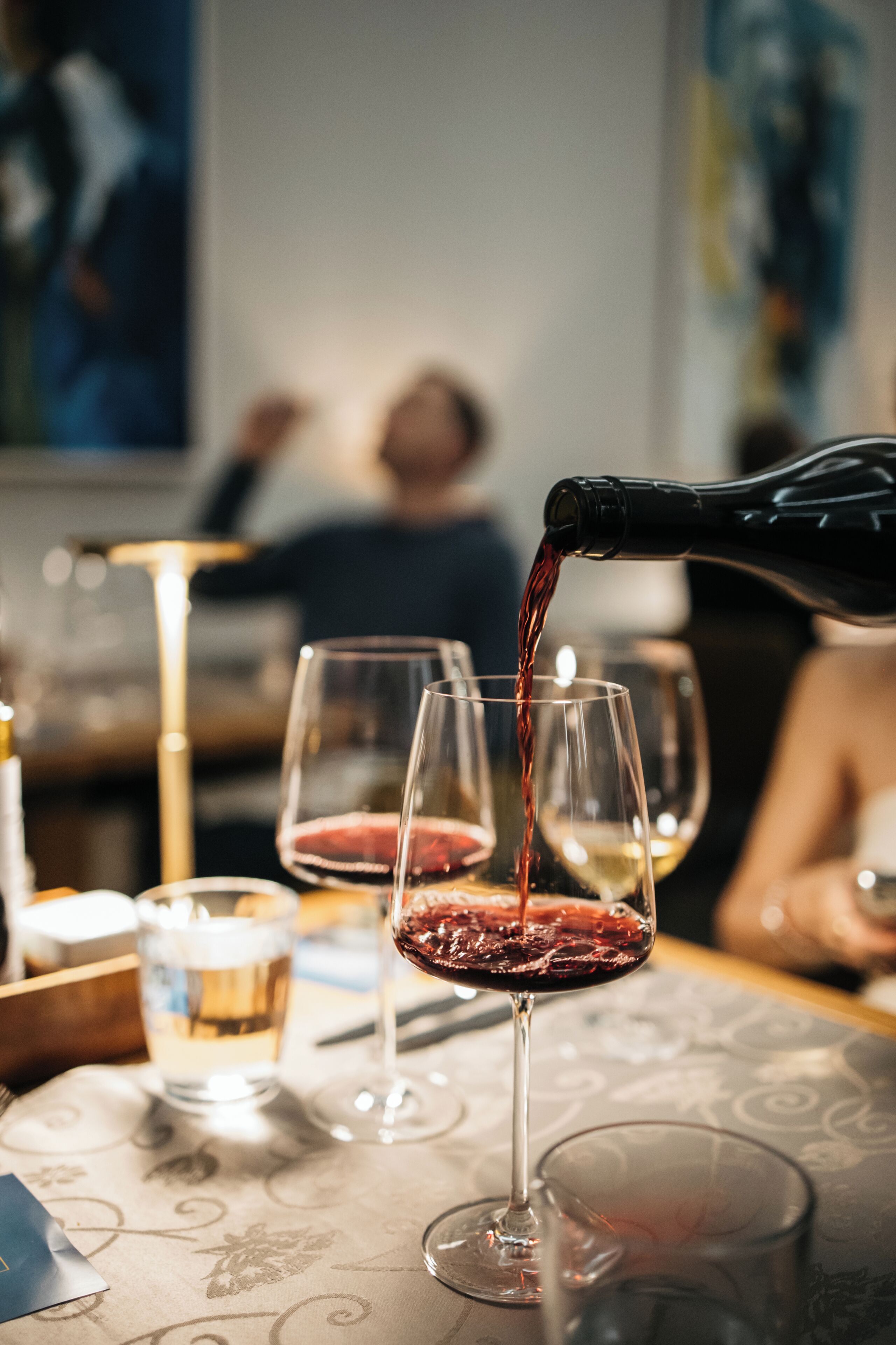 A table with wine glasses and a bottle being poured into one of them.