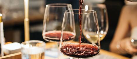 A table with wine glasses and a bottle being poured into one of them.