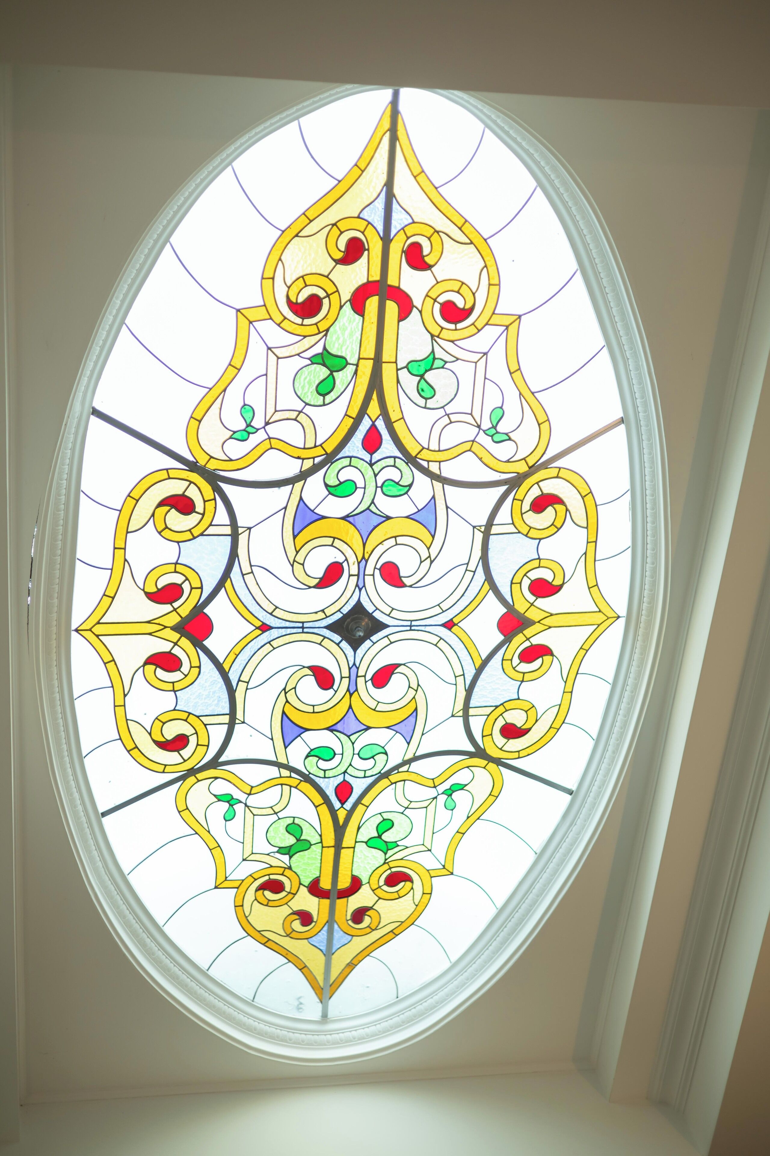 A stained glass window with intricate designs and a symmetrical pattern.