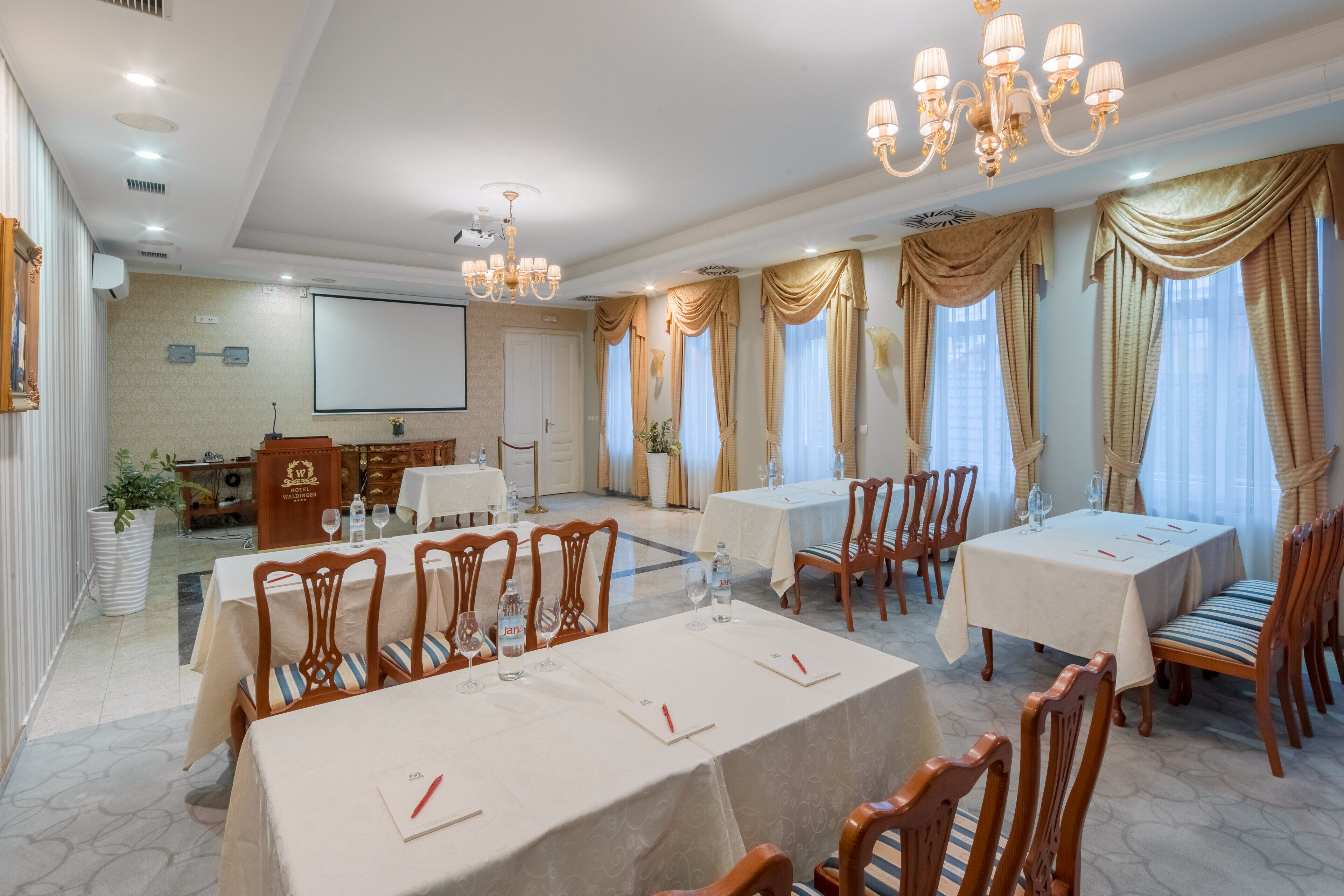 A conference room with tables, chairs, and a projector screen.