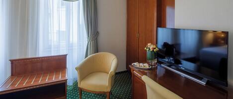 Una habitación de hotel con un sofá de madera, una silla, un televisor y un armario.