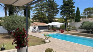 A pool area with a tiled deck, lounge chairs, and a small garden with potted plants. - Villa with swimming pool in Pertuis Sud Luberon in Provence (Pertuis)