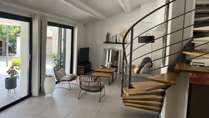 A modern living room with a wooden staircase, a television, and a dining area. - Villa with swimming pool in Pertuis Sud Luberon in Provence (Pertuis)