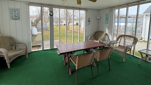 A covered patio with a table and chairs, a ceiling fan, and a view of the backyard. - Sunshine House - 3BR home close to everything, screen porch! No Linens (Chincoteague)