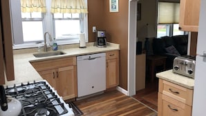 A compact kitchen with a gas stove, dishwasher, coffee maker, and a toaster. - Sunshine House - 3BR home close to everything, screen porch! No Linens (Chincoteague)